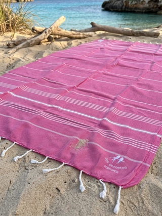 Toalla de playa rosa con rayas blancas con logo de Ses Orenetes